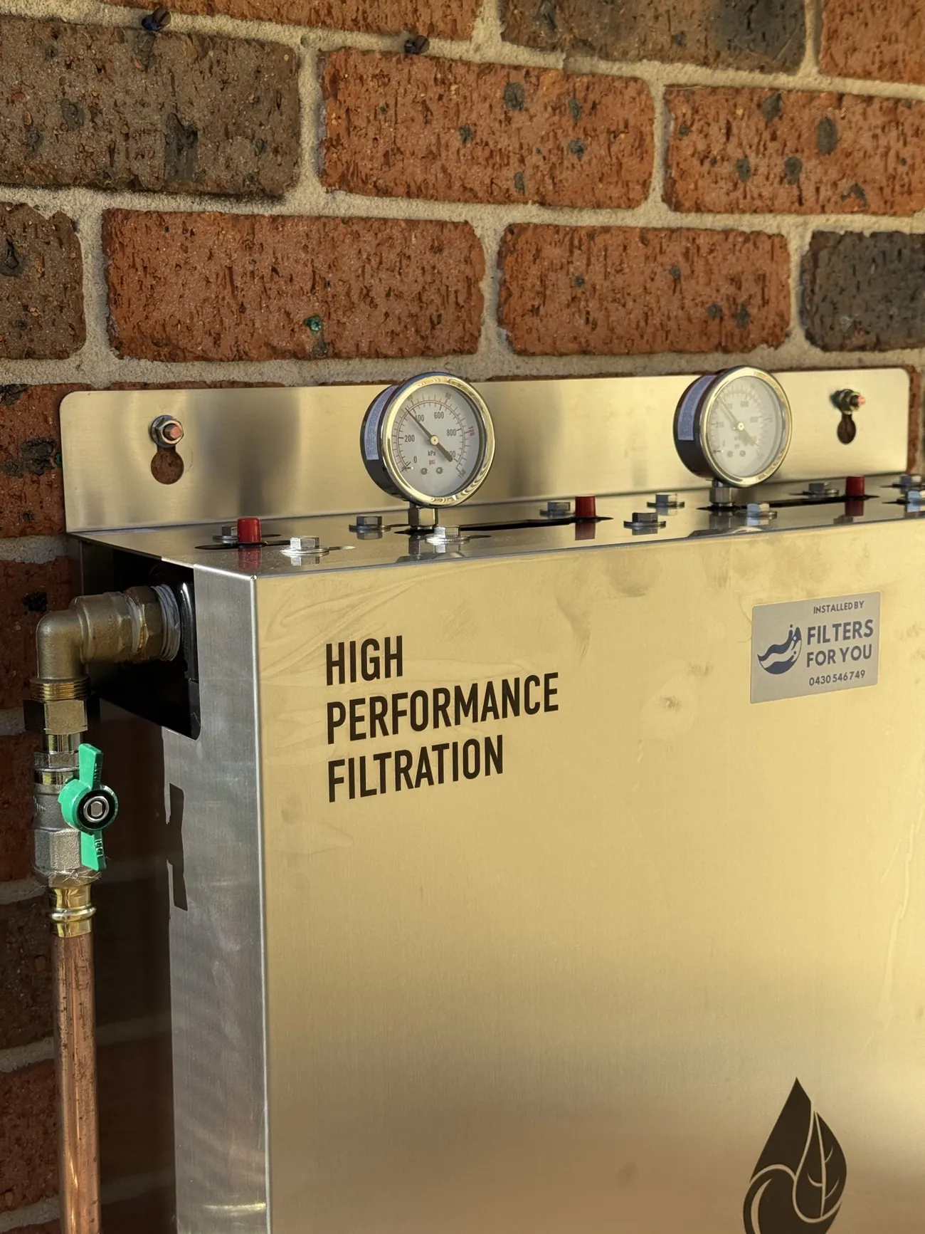 A Filters For You whole house filtration system installed on a Sydney brick wall, pressure gauges and copper pipework visible