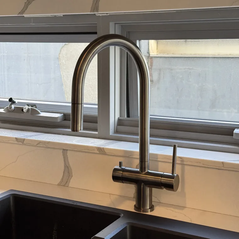 A 3 way mixer tap in brushed nickel at a stone benchtop