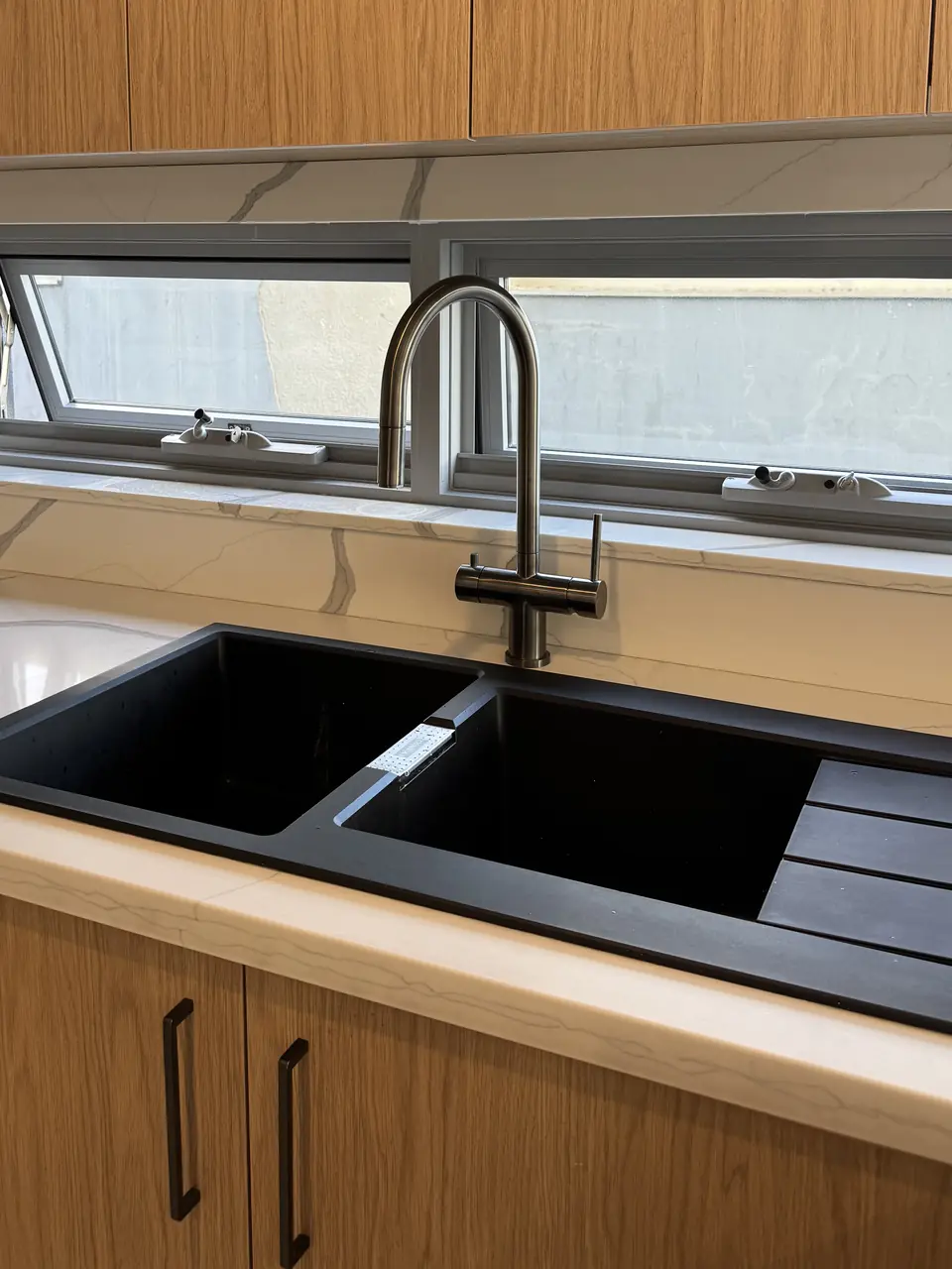 A brushed three way mixer installed over a black double sink