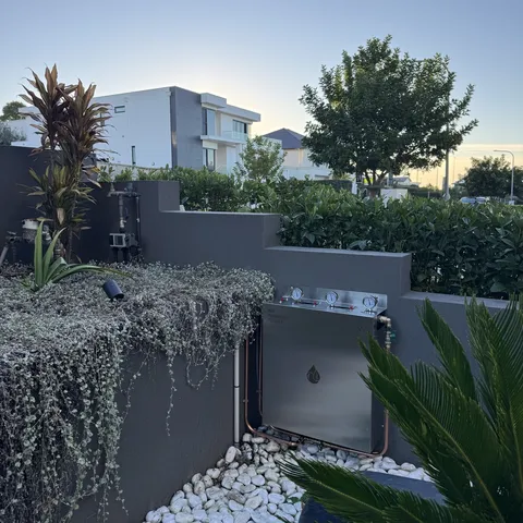 A whole house filtration unit on a landscaped Sydney garden bed at dusk