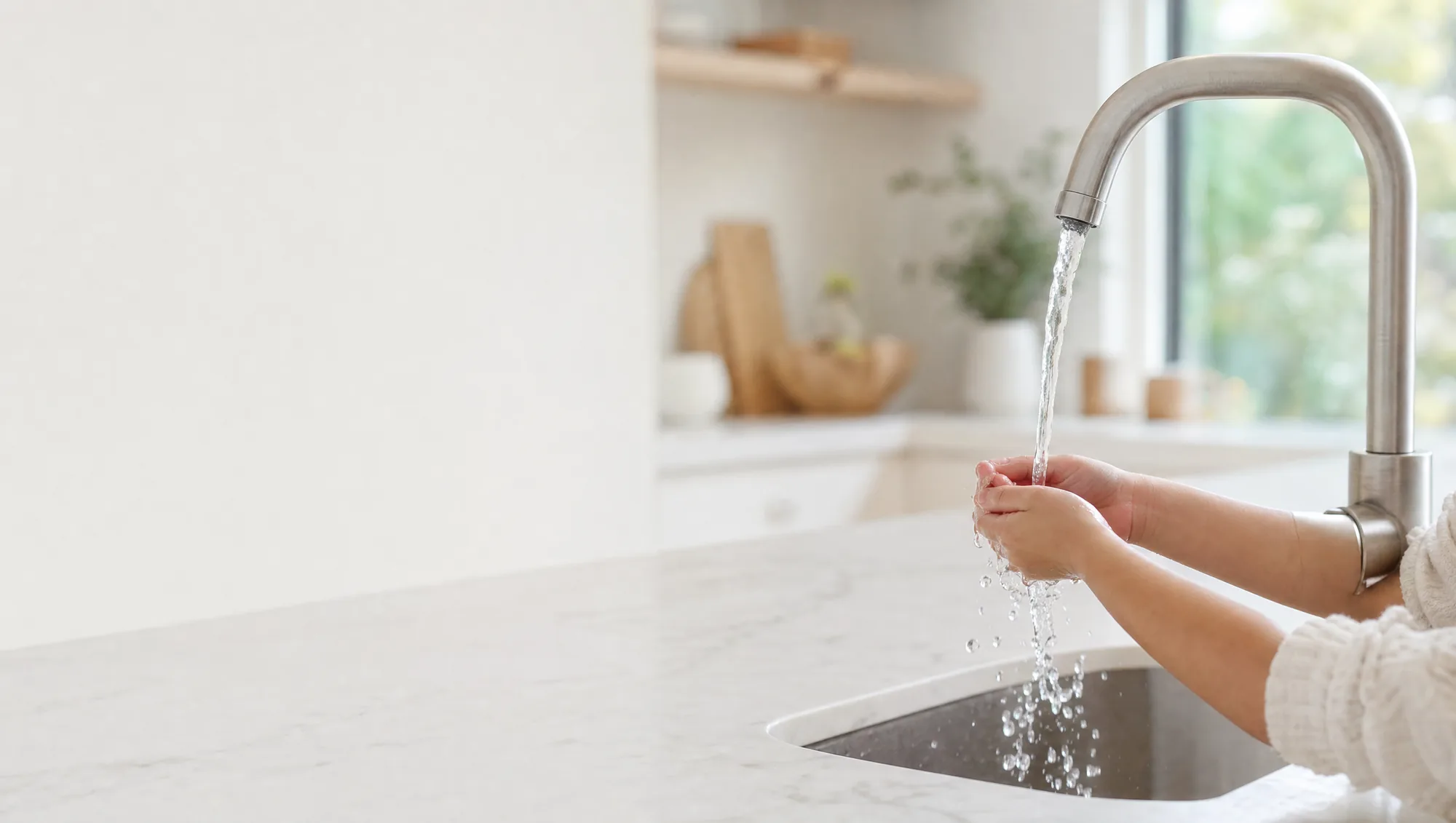 A child washing their hands under a kitchen tap